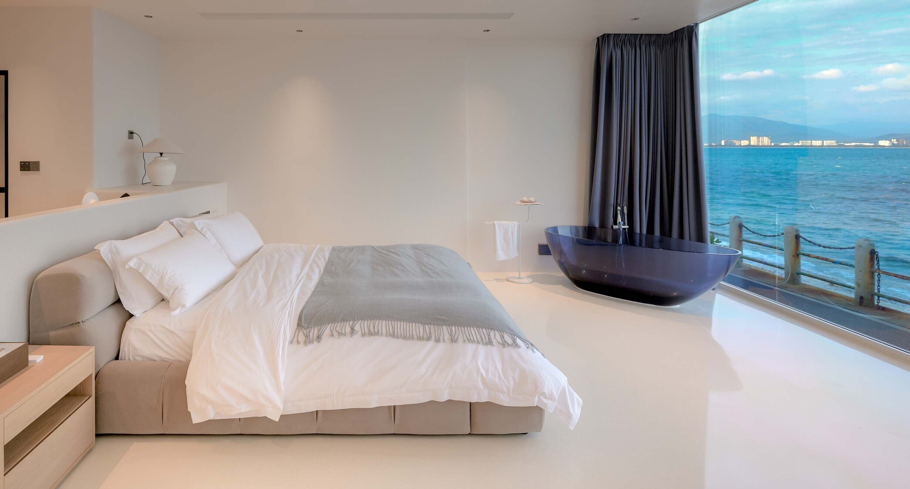 Un dormitorio moderno con una cama grande, una zona de estar integrada y vistas al mar.