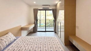 Una camera da letto con un letto, una panca, un armadio e un balcone con tende.
