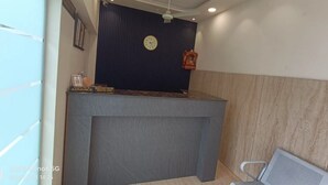 A reception desk with a clock, framed pictures, and a sign indicating advance payment. - MI Rooms (Hoshiarpur)