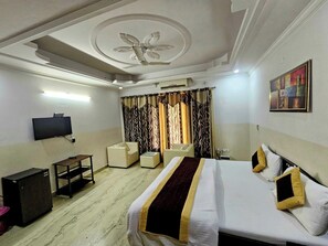 A hotel room with a bed, a desk, a chair, a television, and a painting on the wall. - Hotel star Residency (Gurugram)