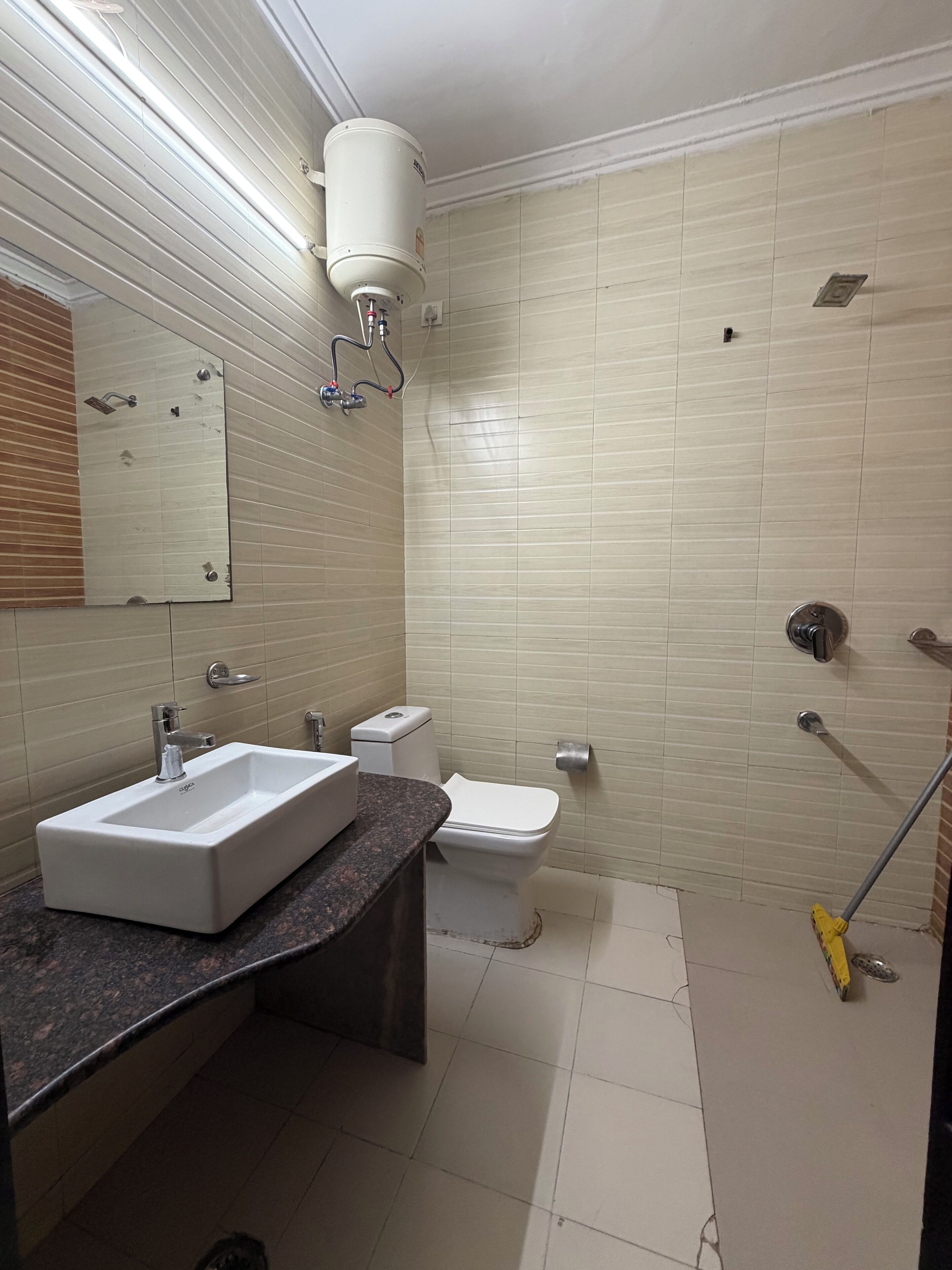 A bathroom with a rectangular sink, toilet, and shower area.