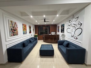 A modern lobby with two dark blue sofas, a central ottoman, and a reception desk. - Hotel star Residency (Gurugram)