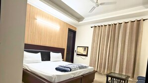 Une chambre d’hôtel moderne avec un grand lit, un ventilateur de plafond, une petite table et un téléviseur.