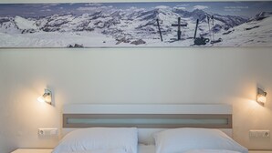 Una habitación de hotel con una cama, dos mesitas de noche y una lámpara fijada a la pared.