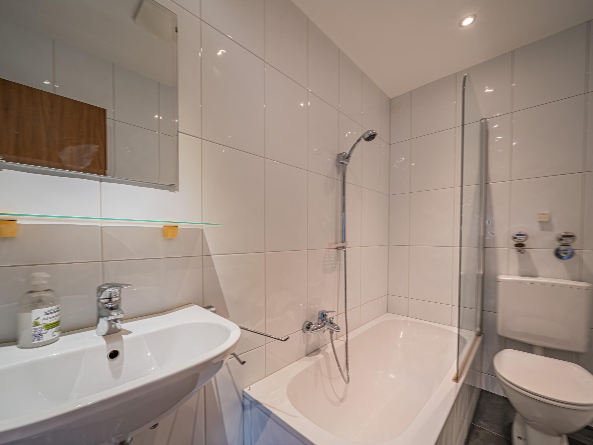 Een moderne badkamer met een wit wastafelmeubel, spiegel en bad.