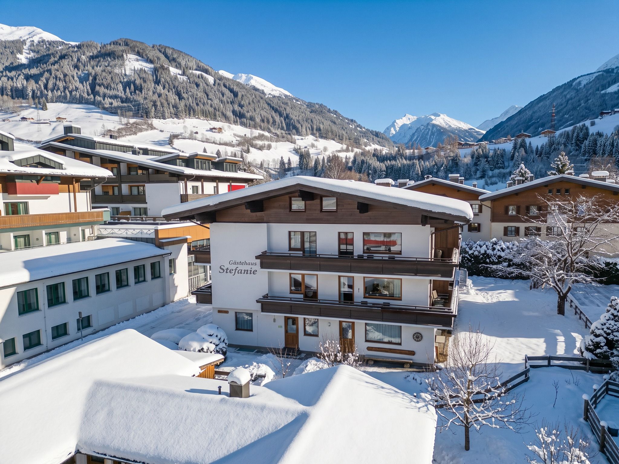 Et hotel med flere etager og sneklædt tag, beliggende i et bjergrigt område med tydeligt afgrænsede skiområder.