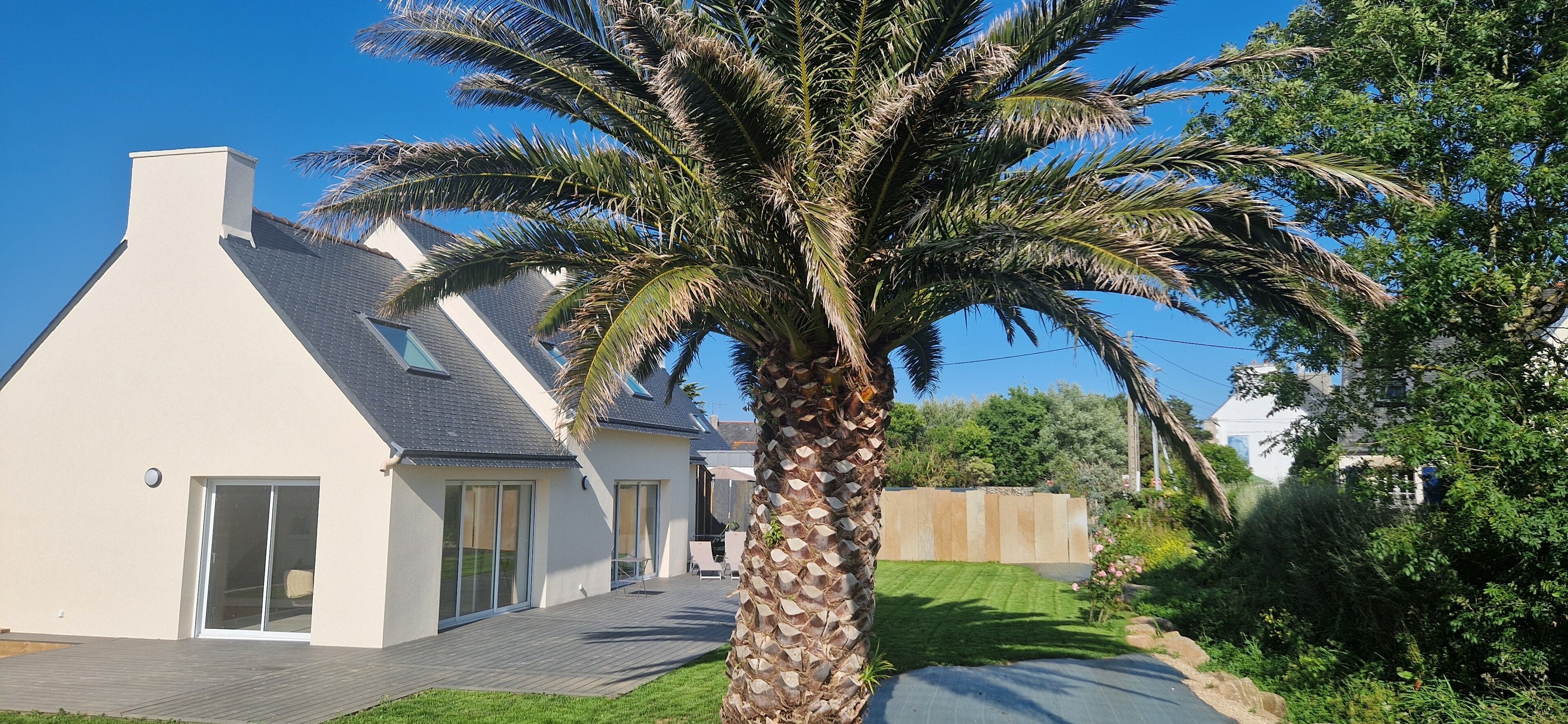 A modern house with a sloped roof, large glass doors, and a well-maintained lawn.