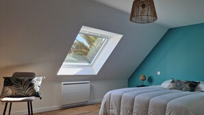 A bedroom with a skylight, a bed, a chair, and a bedside table. - The house West side, SPA, Sea at 80 meters (Plounéour-Brignogan-plages)