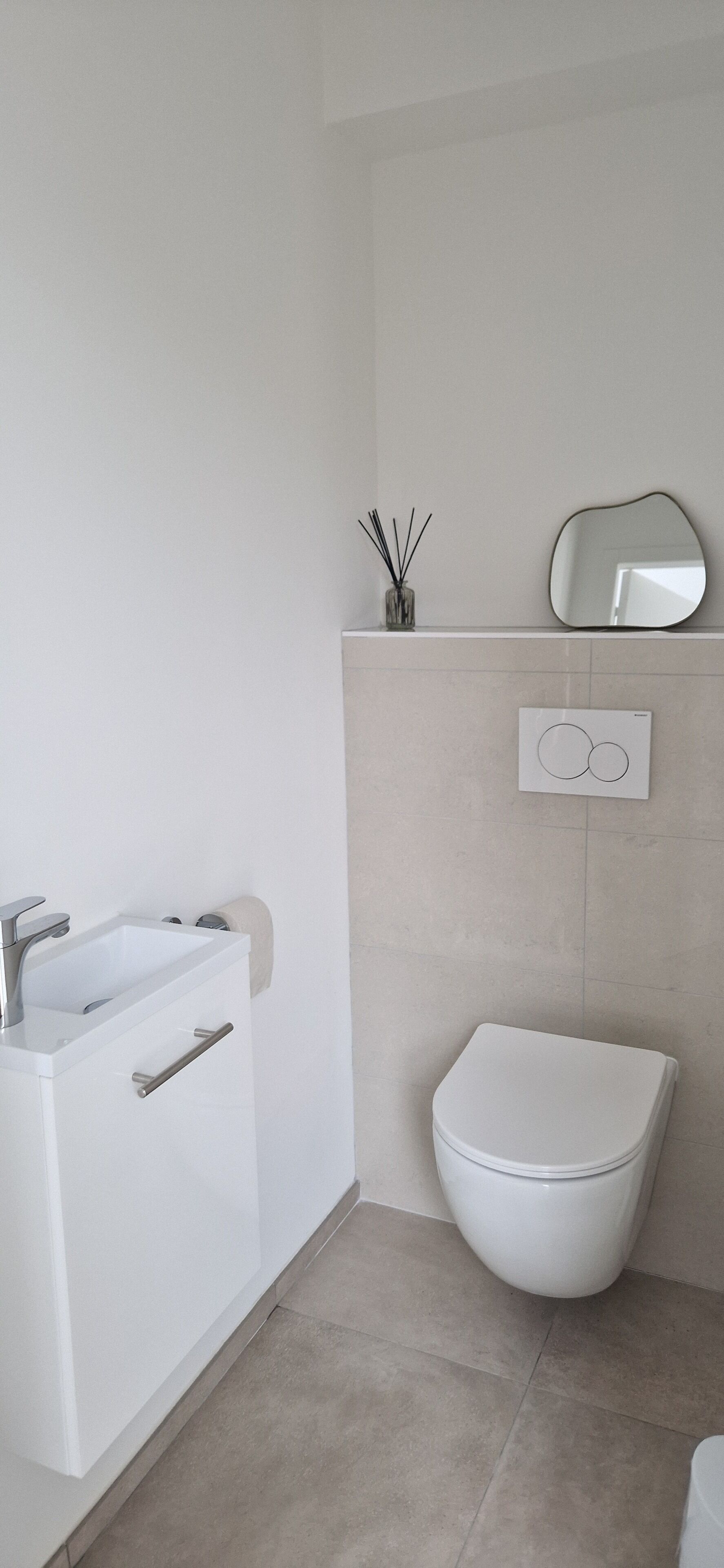 A modern bathroom with a white bathtub, a toilet, and a wall-mounted mirror.