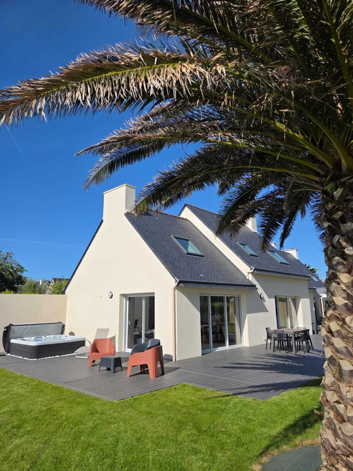 A modern house with a sloped roof, large windows, and a patio area with outdoor furniture.