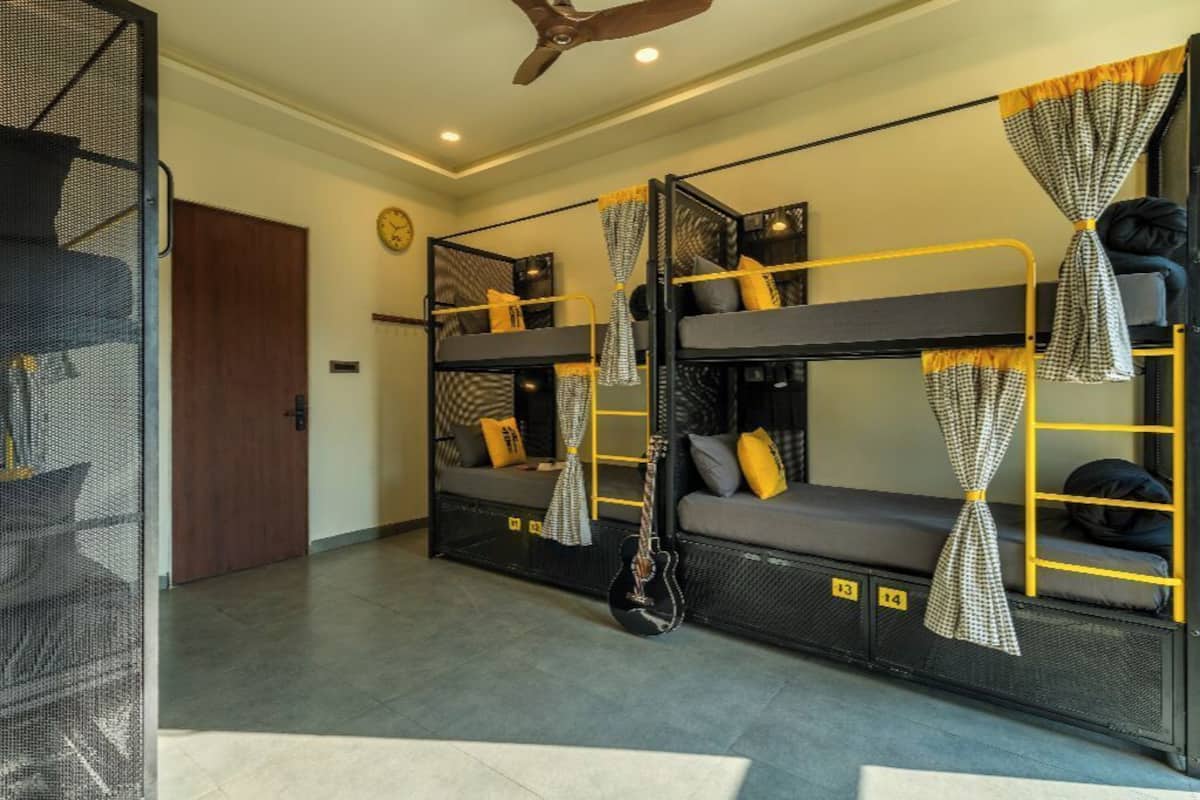 A dormitory room with bunk beds, a guitar, and a door.
