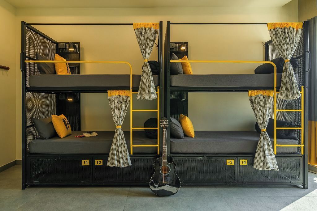 A bunk bed room with a guitar, checkered curtains, and numbered storage compartments.