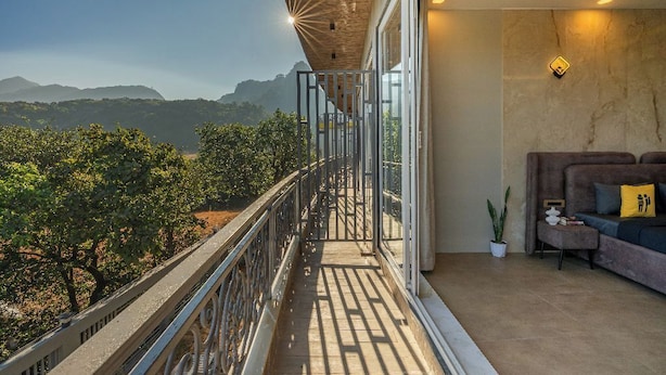 A balcony with a view of mountains, a sofa with cushions, and a potted plant. - The Hosteller Bam Lonavala, Tiger Point (Paud)