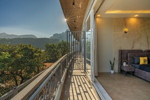 Un balcon avec vue sur les montagnes, un canapé avec des coussins et une plante en pot.