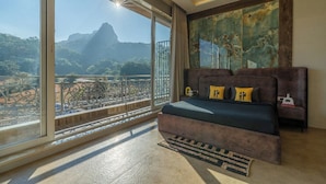 A bedroom with a large window, a bed, a sofa, and a painting. - The Hosteller Bam Lonavala, Tiger Point (Paud)