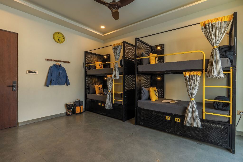 A room with bunk beds, a clock, a coat rack, and a suitcase.