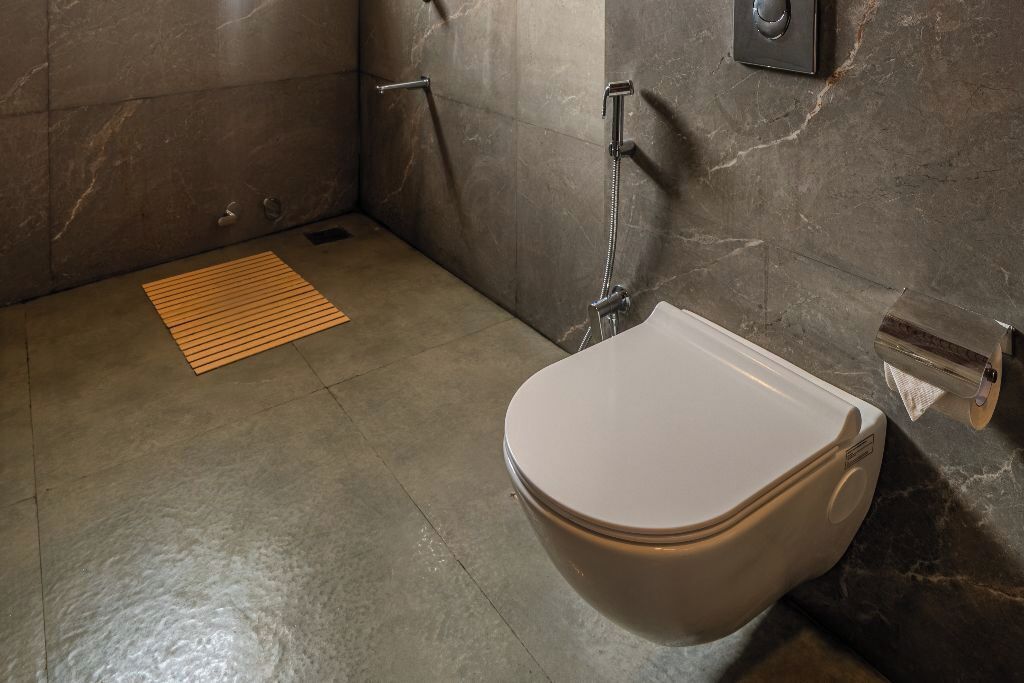 A bathroom with a toilet, a shower, and a towel dispenser.