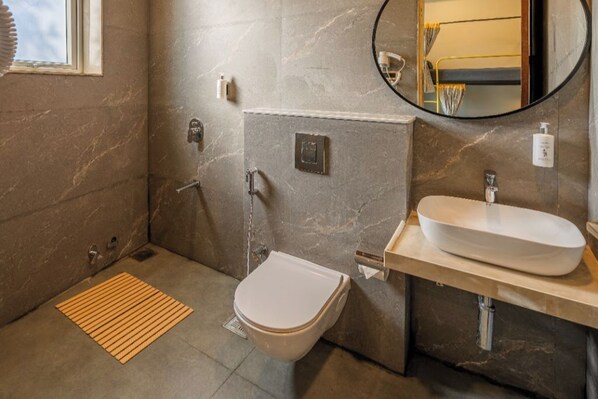 A bathroom with a marble wall, a white sink, a toilet, and a shower. - The Hosteller Bam Lonavala, Tiger Point (Paud)
