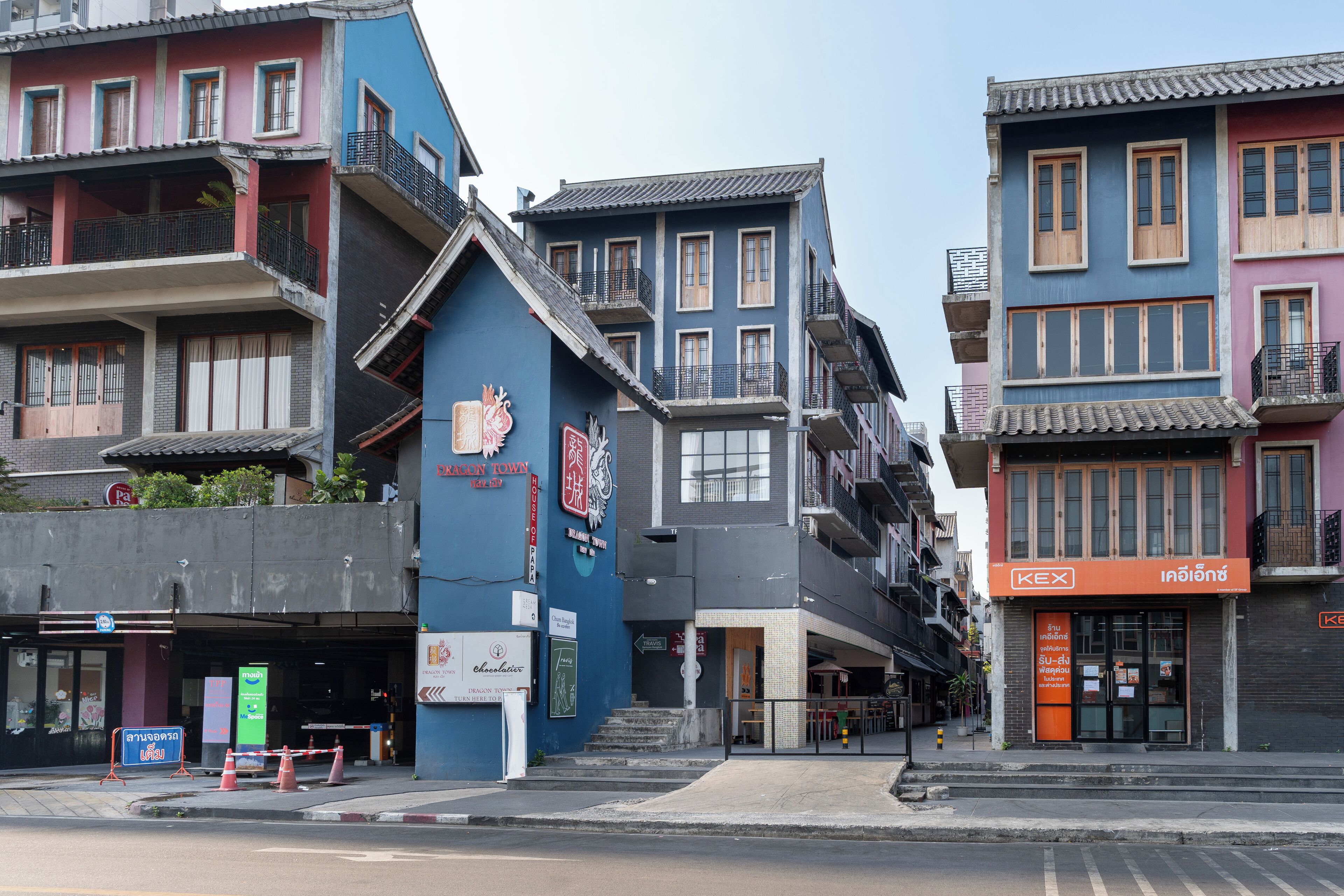 A multi-story building with balconies, a sign for a restaurant, and a storefront with a sign in a foreign language.
