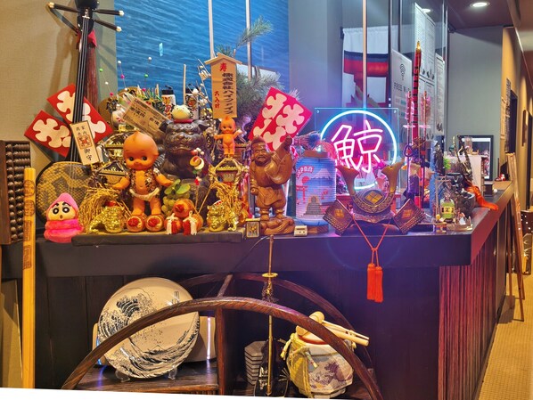 A display of various cultural artifacts and decorations, including figurines, a neon sign, and traditional items. - Kujiranoonaka (Yamanakako)