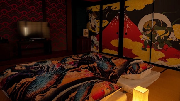 A room with a bed featuring a colorful, abstract design, a television, and a wall with a traditional Japanese pattern. - Kujiranoonaka (Yamanakako)