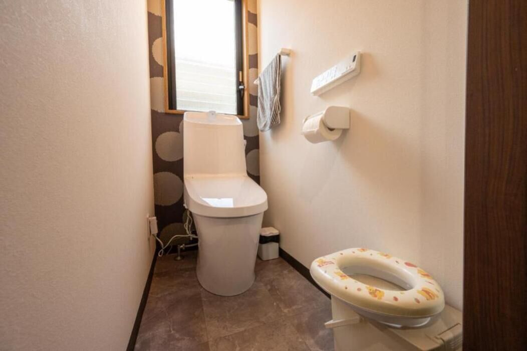 Een kleine badkamer met een toilet, een toiletrolhouder en een toiletrol.