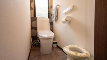 Een kleine badkamer met een toilet, een toiletrolhouder en een toiletrol.