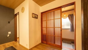 A traditional Japanese room with a sliding door, wooden flooring, a clock on the wall, and a hanging light fixture. - SAKURATARO MOMIJIJIRO NO MIYAKO (Asakura)