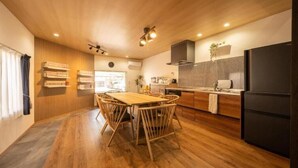 A modern kitchen with wooden flooring, a dining table with chairs, and a black refrigerator. - SAKURATARO MOMIJIJIRO NO MIYAKO (Asakura)