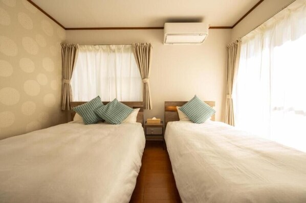 Une chambre d’hôtel avec deux lits, une table de chevet et un appareil de climatisation.