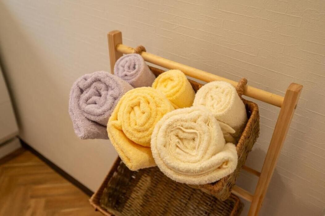 A wooden chair with a woven basket holding rolled towels in various colors.
