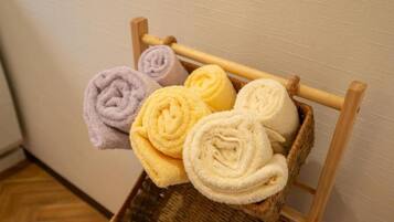 A wooden chair with a woven basket holding rolled towels in various colors.