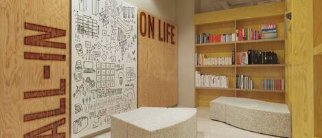 Una biblioteca moderna con un gran mural en la pared, estanterías y zonas de estar.