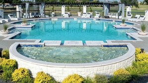 A circular pool with a hot tub in the center, surrounded by lounge chairs and planters. - Universal Kids Resort Frisco Cozy 2-bedroom apartment with pool and gym access (Frisco)