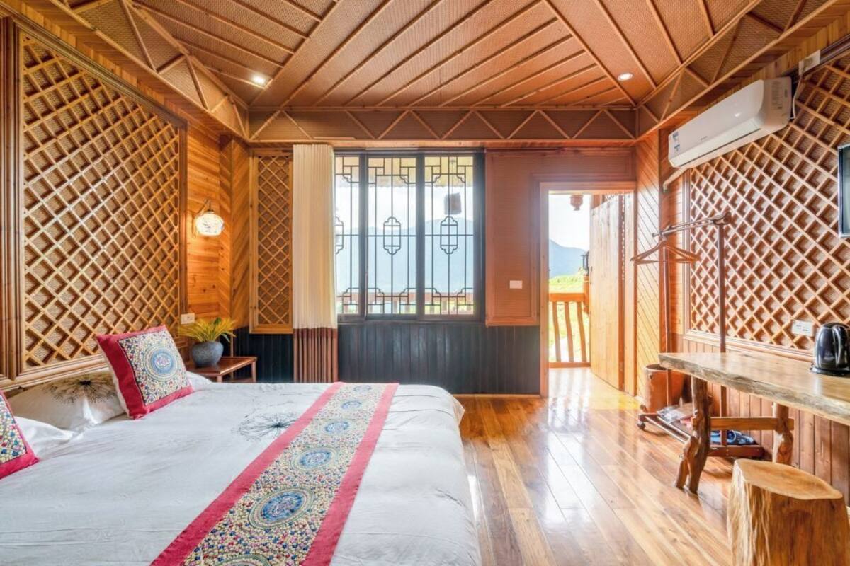 Una habitación de madera con una cama, un escritorio y una ventana con vistas.