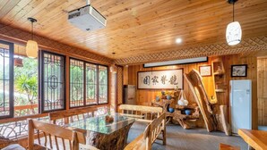 Un interno in legno con un tavolo da pranzo in vetro, sedie di legno e un proiettore a soffitto.