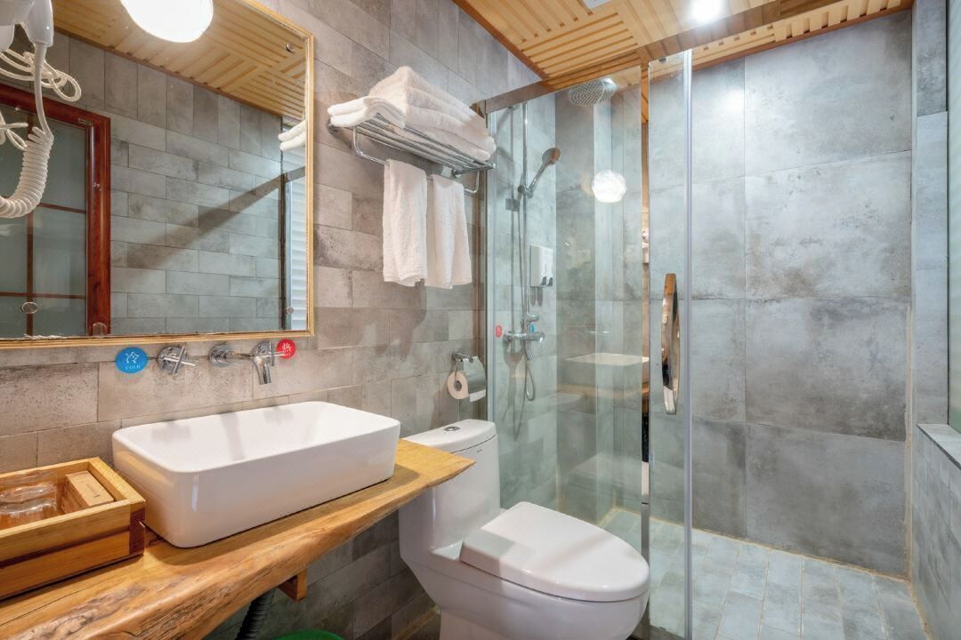 Un baño moderno con un lavamanos grande, inodoro y cabina de ducha de vidrio.