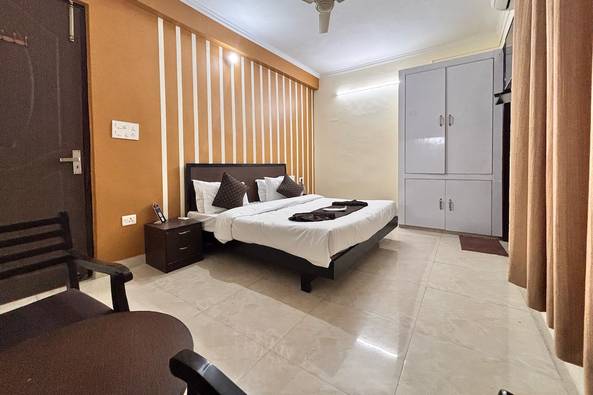 Une chambre d’hôtel équipée d’un lit, d’une table de chevet, d’une armoire et d’un ventilateur de plafond.