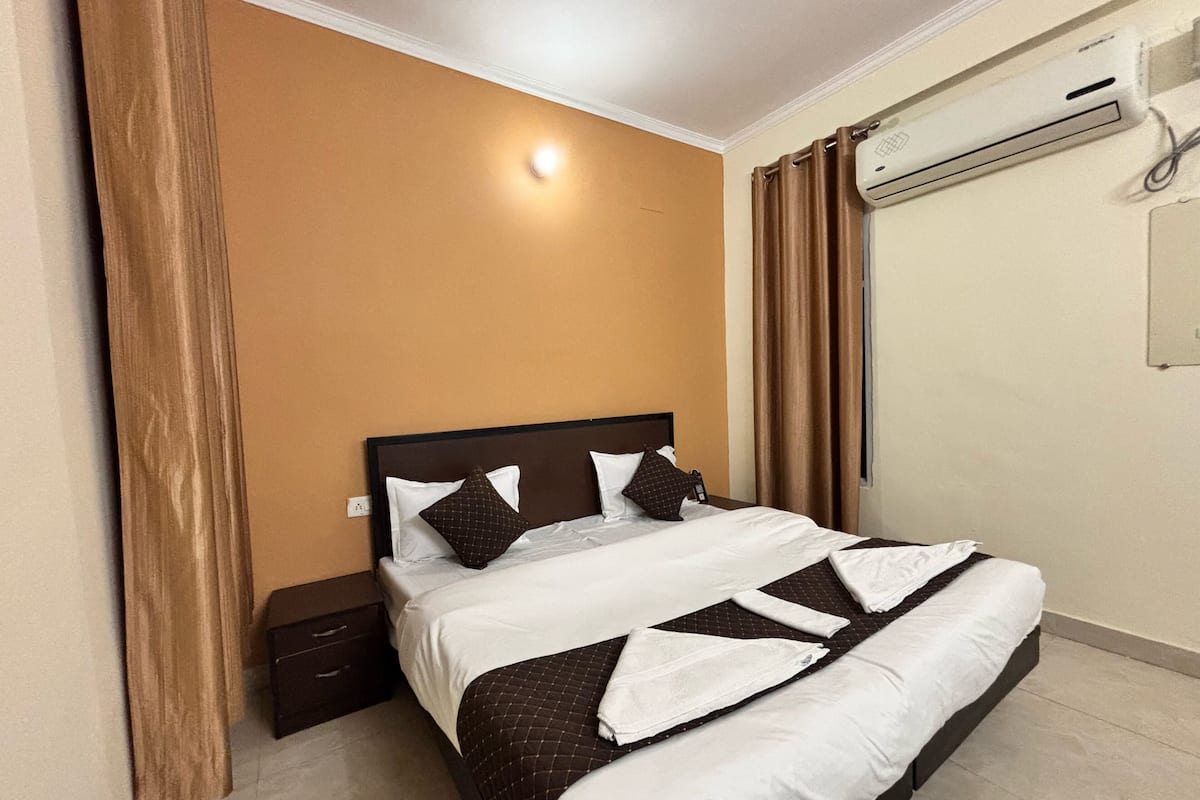Une chambre d’hôtel avec un lit, une table de chevet, un climatiseur et des rideaux.
