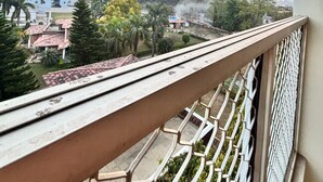 A balcony with a metal railing overlooking a residential area with houses and trees. - The Shivaay AIIMS by Lovely Hospitality (Rishikesh)
