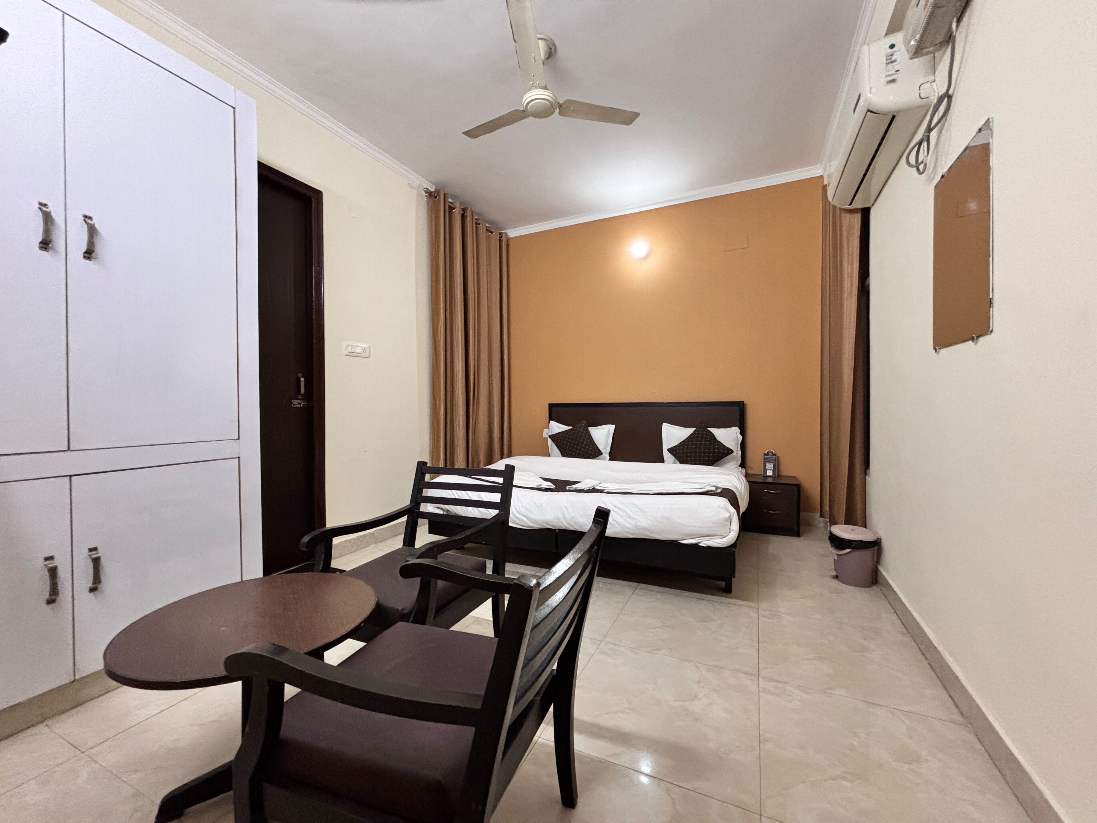 Une chambre d’hôtel équipée d’un lit, d’un bureau, d’une chaise, d’un ventilateur de plafond et d’un appareil de climatisation.