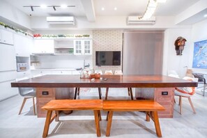 A modern kitchen with a central island, built-in appliances, and a dining area with a bench. - Penghu I Stay I B&B (Penghu)