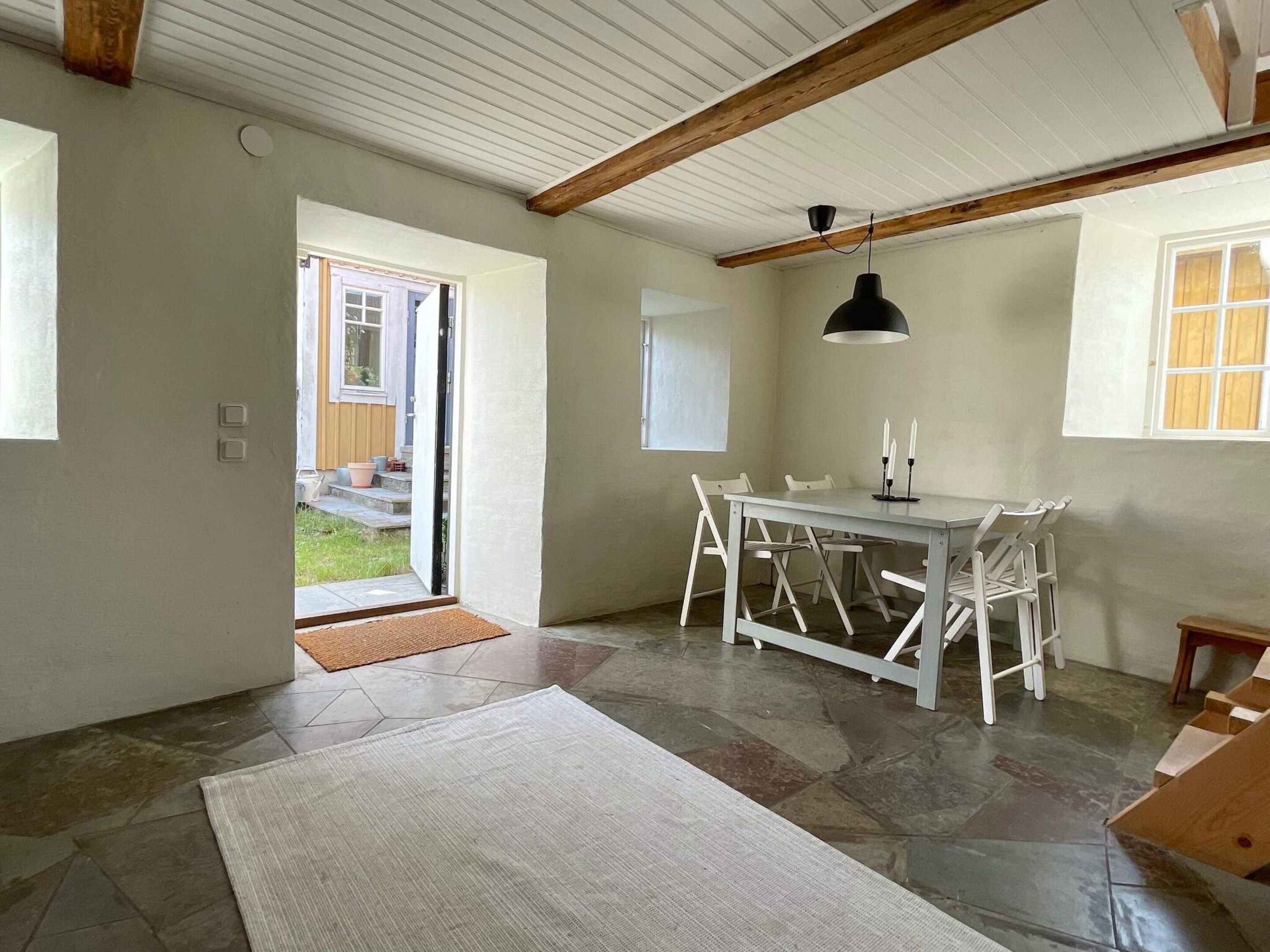 Una habitación con una mesa de comedor, sillas, un tapete, un ventilador de techo y una ventana.