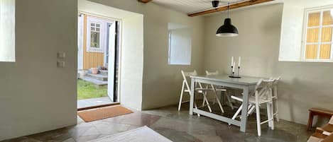 A room with a dining table, chairs, a rug, a ceiling fan, and a window.