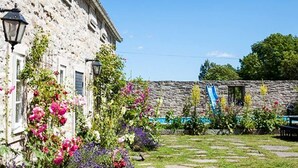 Un edificio in pietra con un giardino che presenta diversi fiori e un muro in pietra con uno scivolo blu.