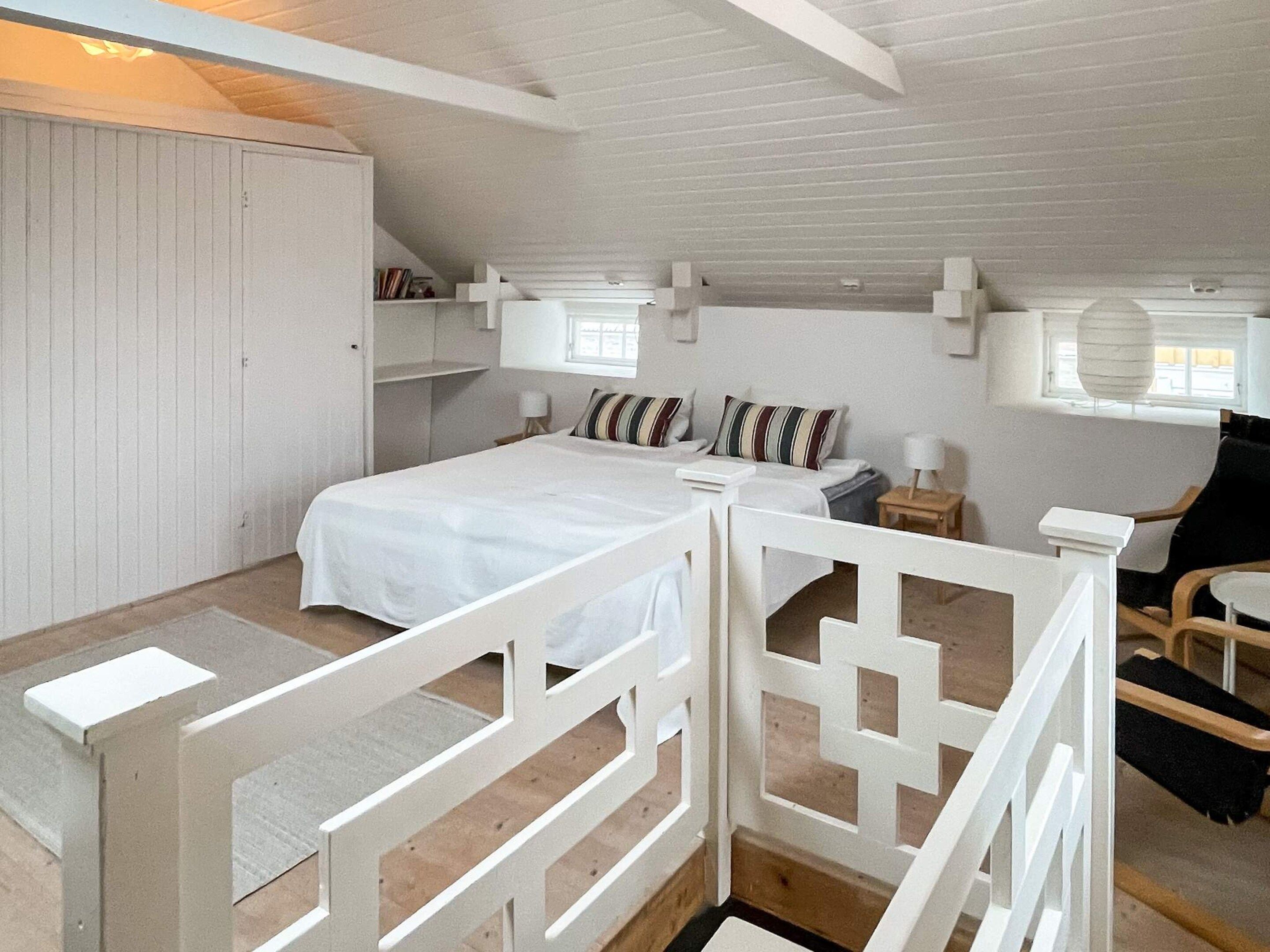 Une chambre à coucher avec un lit, des tables de chevet, une chaise et une armoire.