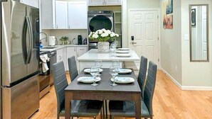 A modern kitchen with a dining area, stainless steel appliances, and a central island with a sink. - 51.Peaceful, modern 3BR Home Near Encore Casino, 12min to Boston (Everett)
