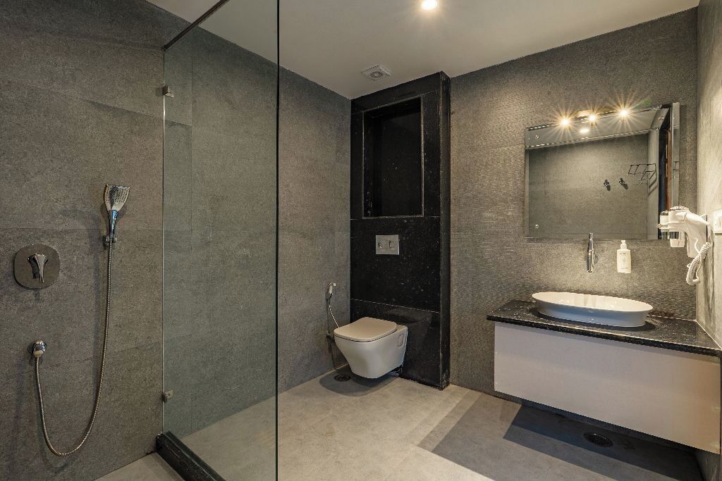A modern bathroom with a glass-enclosed shower, a toilet, and a vanity with a sink and mirror.
