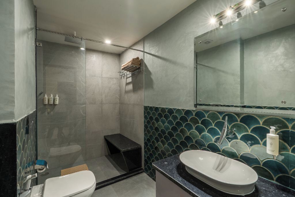 A modern bathroom with a glass-enclosed shower, a white sink, and a tiled backsplash.