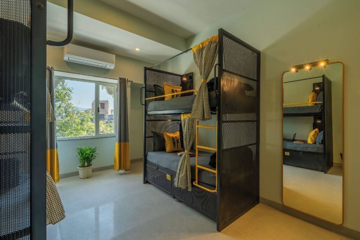 A compact room with bunk beds, a large mirror, and a potted plant.